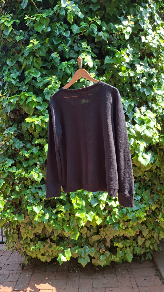 Black bag on a hanger against a green leafy background